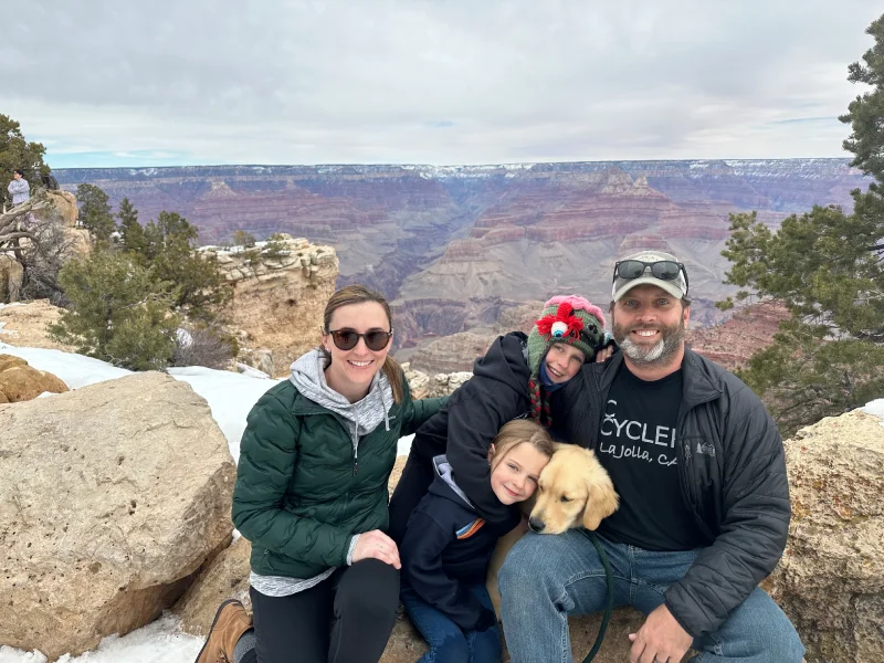 Family with kids and dog posing at Grand Canyon scenic viewpoint.