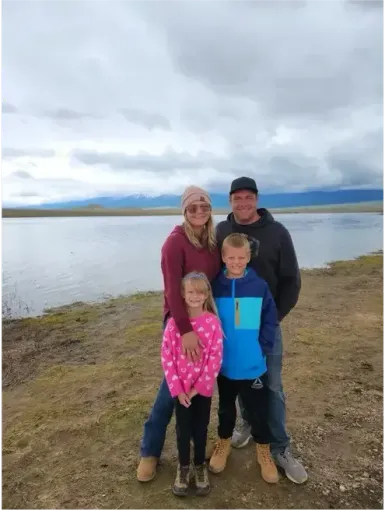 Family with two children standing by a lake on cloudy day.